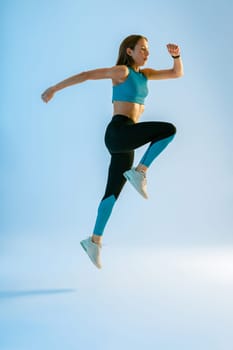 Athletic active fitness woman jumping on studio background . Dynamic movement