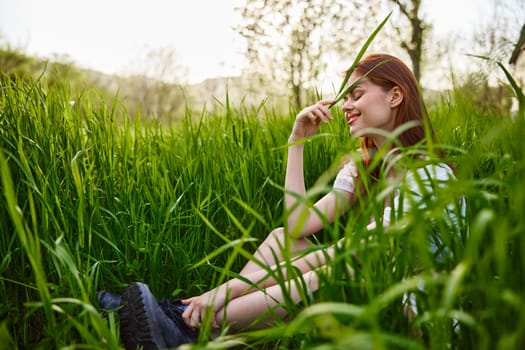 a pretty woman sits in the tall grass enjoying a sunny day and harmony with nature