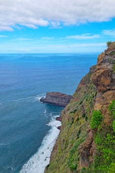 A picturesque cliff from the island of Madeira and a view of the ocean.