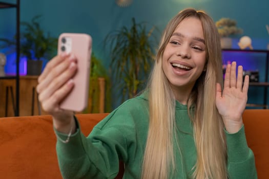 Happy girl blogger taking selfie on smartphone communicating video call home online with subscribers