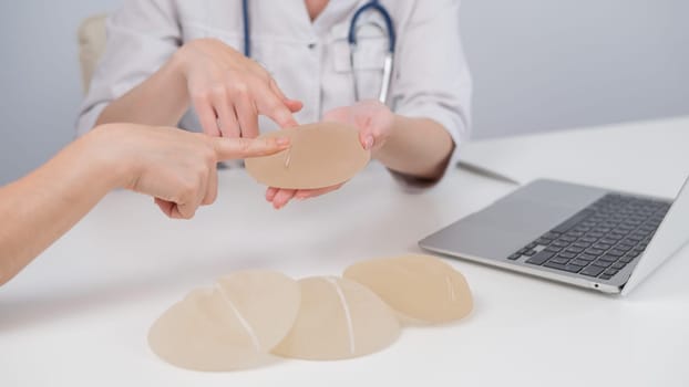 Caucasian woman and plastic surgeon touching and choosing breast implants.