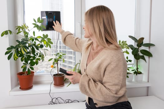 Woman cleaning windows at home with robotic cleaner.