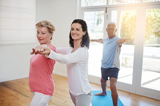 Committed to health. a female yoga instructor working with a senior couple.