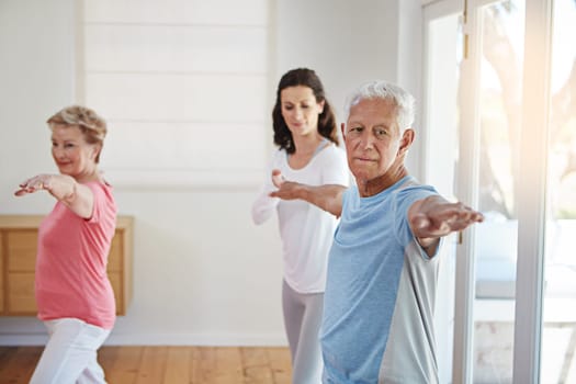 Staying in shape in their senior years. a female yoga instructor working with a senior couple.