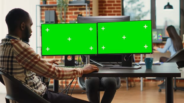 Professional IT expert analyzing greenscreen on multiple monitors