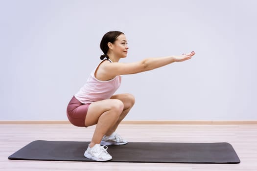 Woman doing fitness at home against wall background