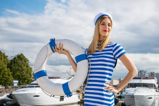 Young woman standing on yacht posing with lifebuoy