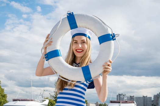 Young woman standing on yacht posing with lifebuoy