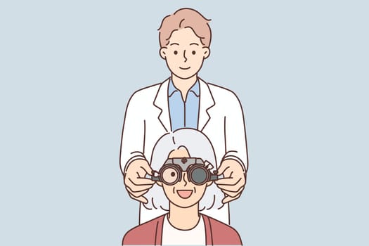 Man optometrist putting on ophthalmic glasses on elderly female patient during vision treatment