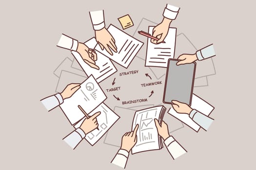 Hands of people over table with documents doing teamwork and strategizing during brainstorming