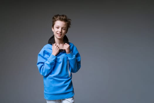 Guy posing in a blue sweatshirt on a gray background