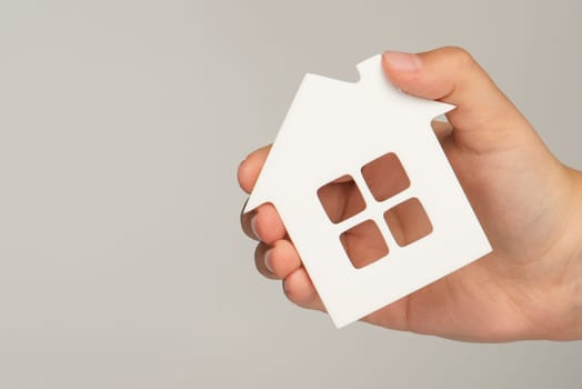 Buying real estate on credit. Model of a white house in hands on a blurred background. Buy a house or apartment, mortgage real estate concept, with copy space