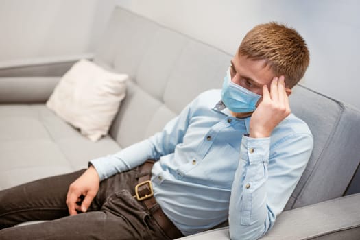 young guy sitting on the couch wearing a medical mask