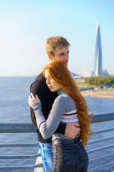 A guy and a girl are standing on the river bridge