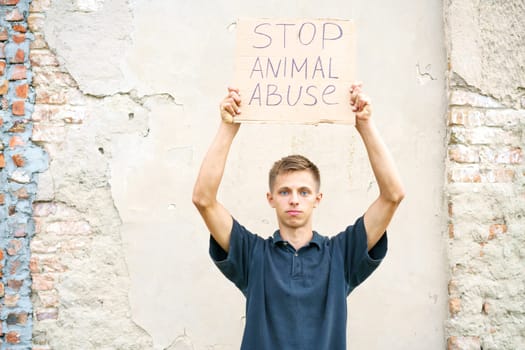Young man holding the inscription stop animal abuse in his