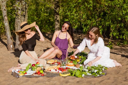 Cheerful women are resting in nature with wine. Beautiful