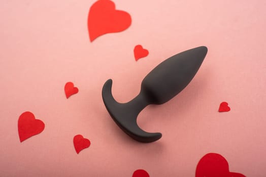 Butt plug and hearts on a pink background. Love symbol for February 14
