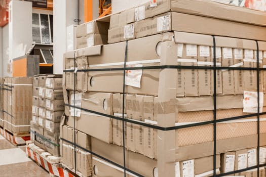 Building materials or construction goods packed in cardboard are stored on a wooden pallet on the warehouse of an industrial plant or hardware store