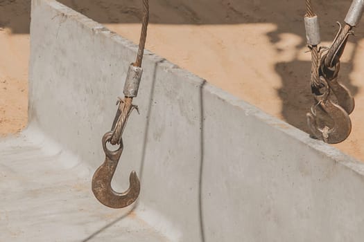Heavy iron hook lifting mechanism with a steel cable rope with a concrete, cement structure on construction site industry