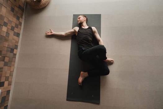 A man performing gymnastic exercises on a yoga mat at home
