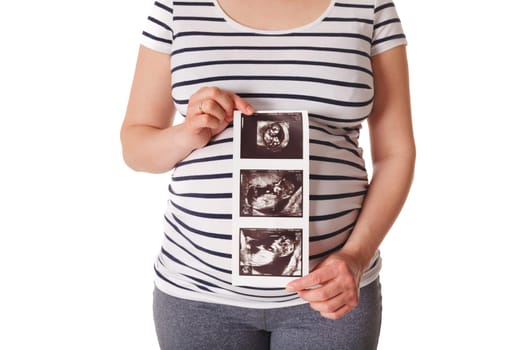 Pregnant woman standing and holding her ultrasound baby scan