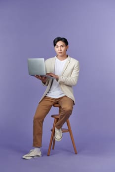 Portrait of smiling young handsome businessman holding and using a laptop