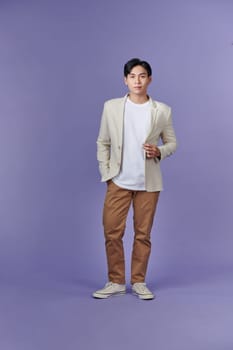 Full length portrait of young handsome southeast Asian millenial businessman on purple