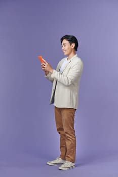 Full body young employee business man hold in hand use mobile cell phone isolated on purple background