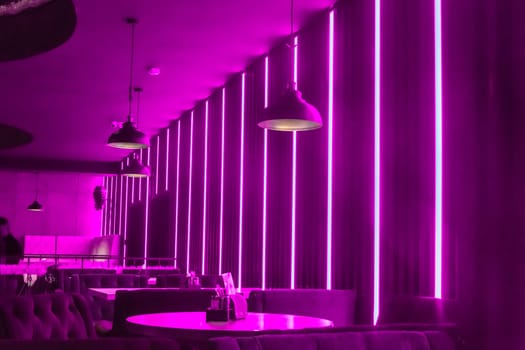 Modern abstract interior of a nightclub with neon purple lighting on the walls
