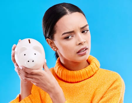 Piggy bank, investment and woman in a studio saving her money for financial growth or profit. Banking, budget and female model with a cash investing plan with finance knowledge by a blue background.
