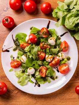Plate of healthy classic top view caprese salad with mozzarella cheese tomatoes and basil in kitchen - italian cuisine top view