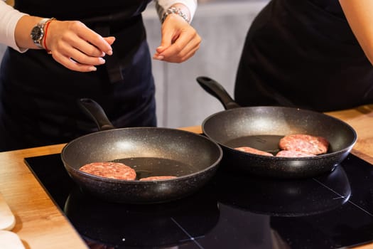 Meat burgers or cutlet-shaped patty being roasting in oil on a frying pan