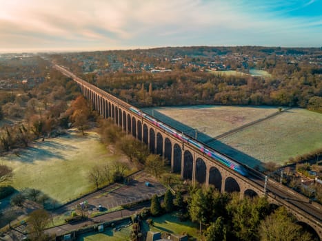 High speed London bound commuter train seen travelling along a viaduct in the late evening