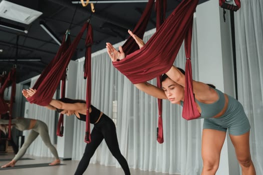 A group of women play sports on hanging hammocks. Fly yoga in the gym
