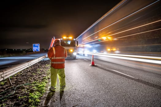 Workers on a Highway at Night With Vehicles Driving Past