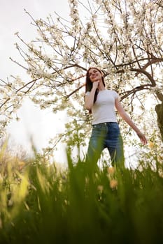 joyful woman stands against the background of a flowering tree in summer clothes. High quality photo