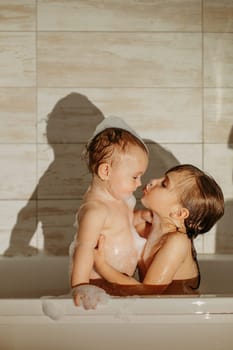 Preschool sister girls play in the bathroom, the older one kisses the younger one