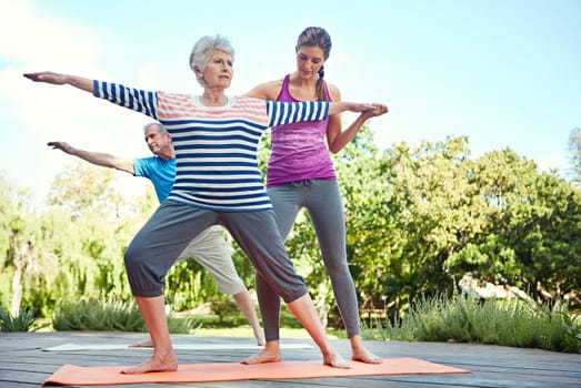 Keep in shape no matter your age. a yoga instructor guiding a senior couple in a yoga class.