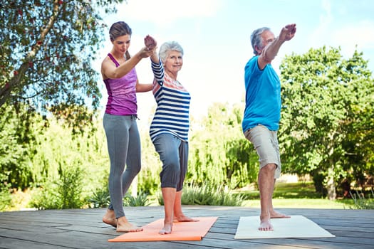 Stay fit in your senior years. a yoga instructor guiding a senior couple in a yoga class.