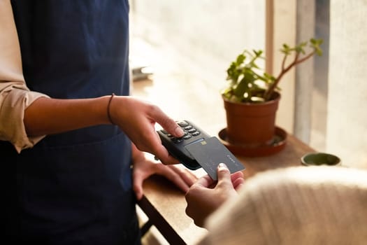 Hand, credit card and pos terminal in a coffee shop for payment by a customer to a waitress for service. Finance, bill and nfc with a person paying using wireless technology in a cafe or restaurant