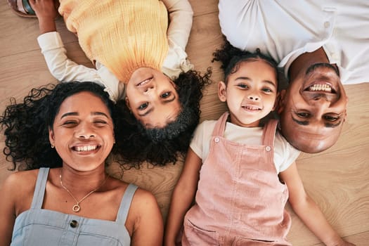 Portrait, above and happy family on a floor, smile and bonding in a living room together. Top view, love and face of children with parents, relax and cheerful while having fun, lying and chilling