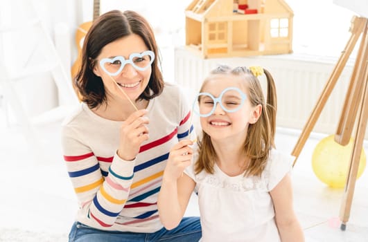 Portrait of smiling mother and daughter with stick glasses