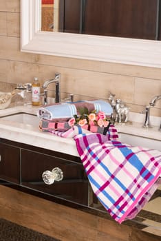 A vertical shot of a plaid pink white towel on a bathroom sink
