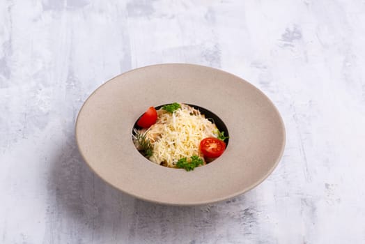 A dish in a beautiful bowl with parmesan on top isolated on a grey background