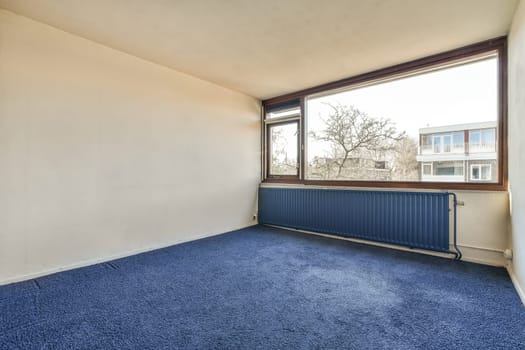 an empty room with a large window and blue carpet