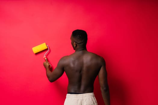 African-American painter on red studio background topless