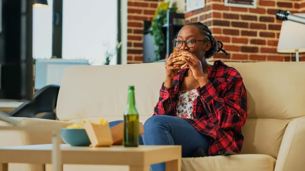 Young woman eating cheeseburger with fries and beer