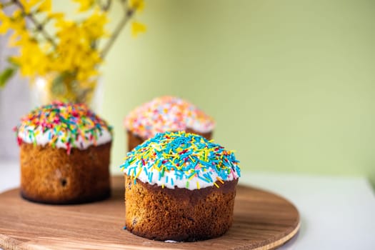 Easter composition with Easter cakes, wooden stand and spring flowers on a yellow background. copy space