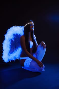 Sexy slim girl with UV makeup posing as angel