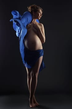 Sensual expectant mother posing with flying cloth
